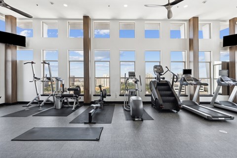 A spacious gym with a variety of equipment and large windows.