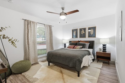 A bedroom with a bed, a ceiling fan, and a rug.