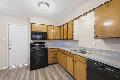A kitchen with wooden cabinets and black appliances.