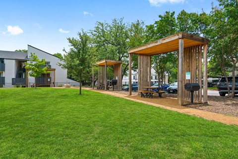 a group of wooden structures on a lawn with grass and trees