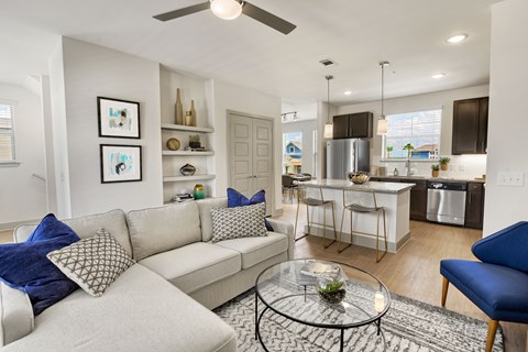 a living room and kitchen with a couch and a glass table