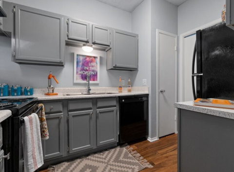 a kitchen with gray cabinets and a black refrigerator