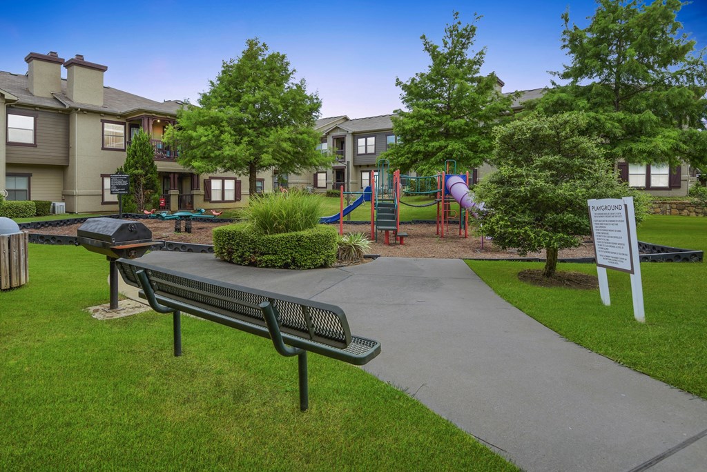 a park with a playground and benches and buildings in the background