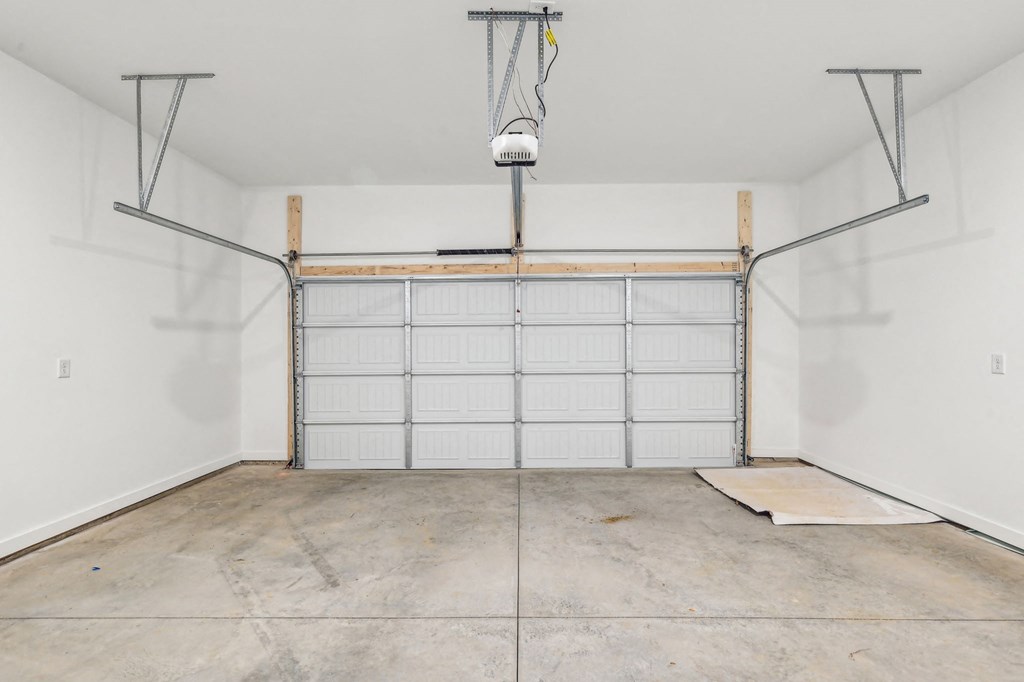 A garage with a white door and a concrete floor.