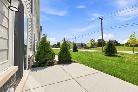 A view of a residential area with a house, trees, and a sidewalk.