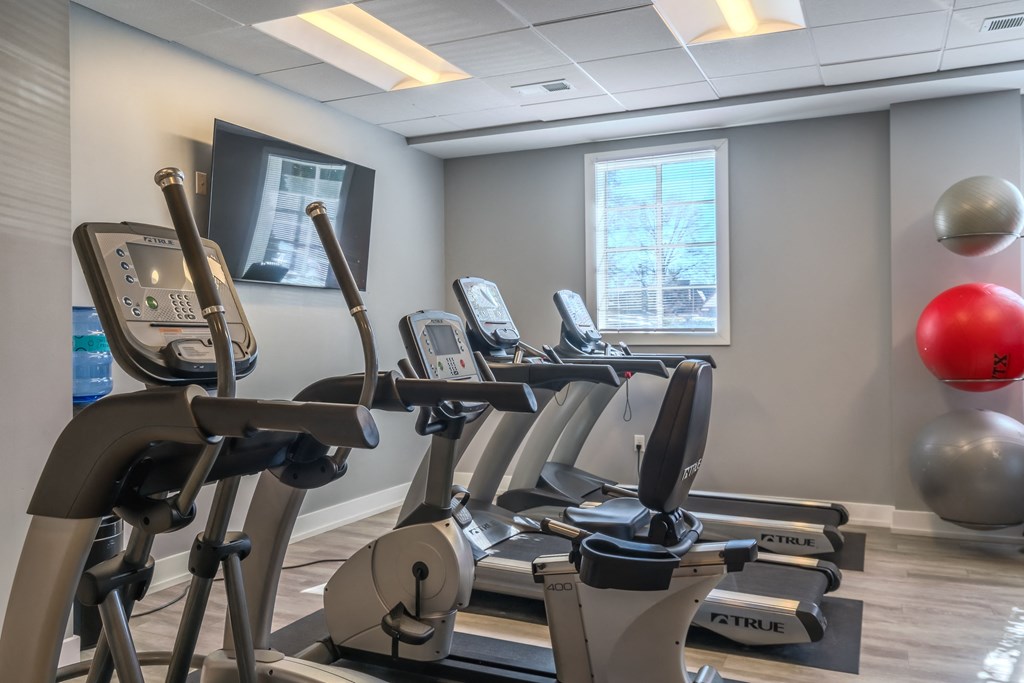a gym with cardio equipment and a large window