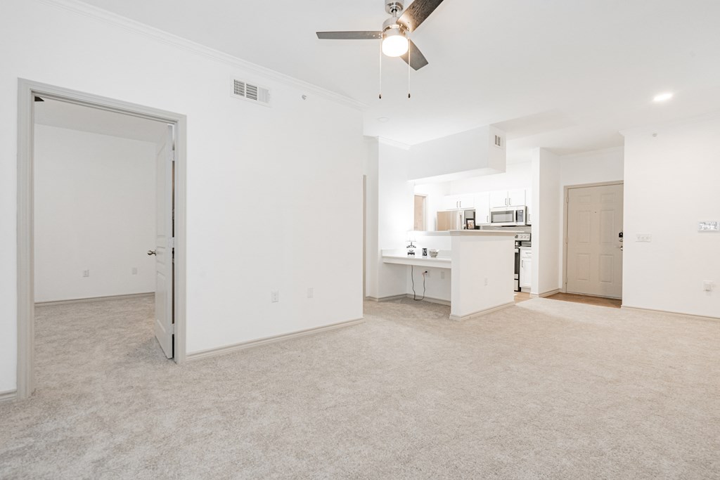 an empty living room and kitchen with a ceiling fan