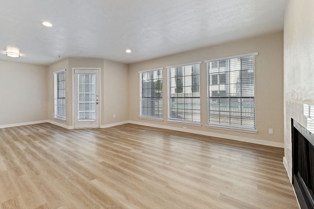 an empty living room with a fireplace and large windows