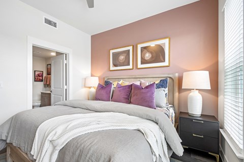 A bedroom with a large bed and two lamps.