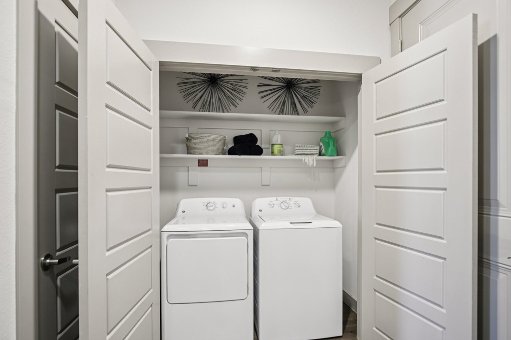 A laundry room with two washing machines and a shelf above them.