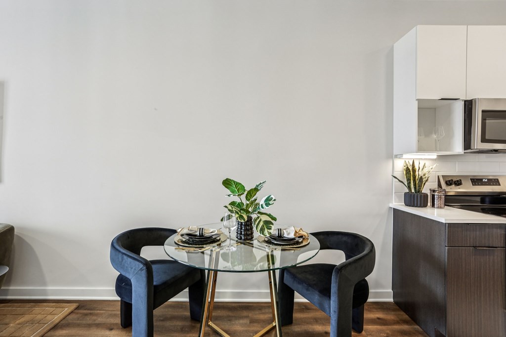 A modern dining area with a glass table and blue chairs.