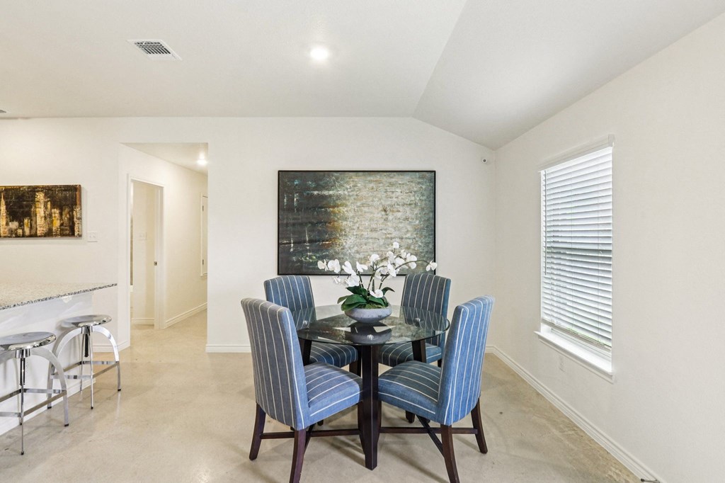 A dining room with a glass table and blue striped chairs.