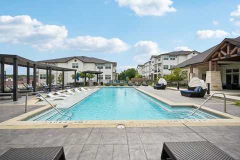 A large outdoor swimming pool with loungers and a building in the background.