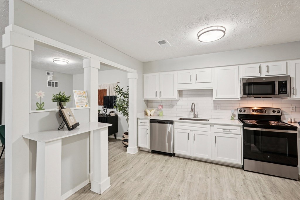 A kitchen with white cabinets and a wooden island.