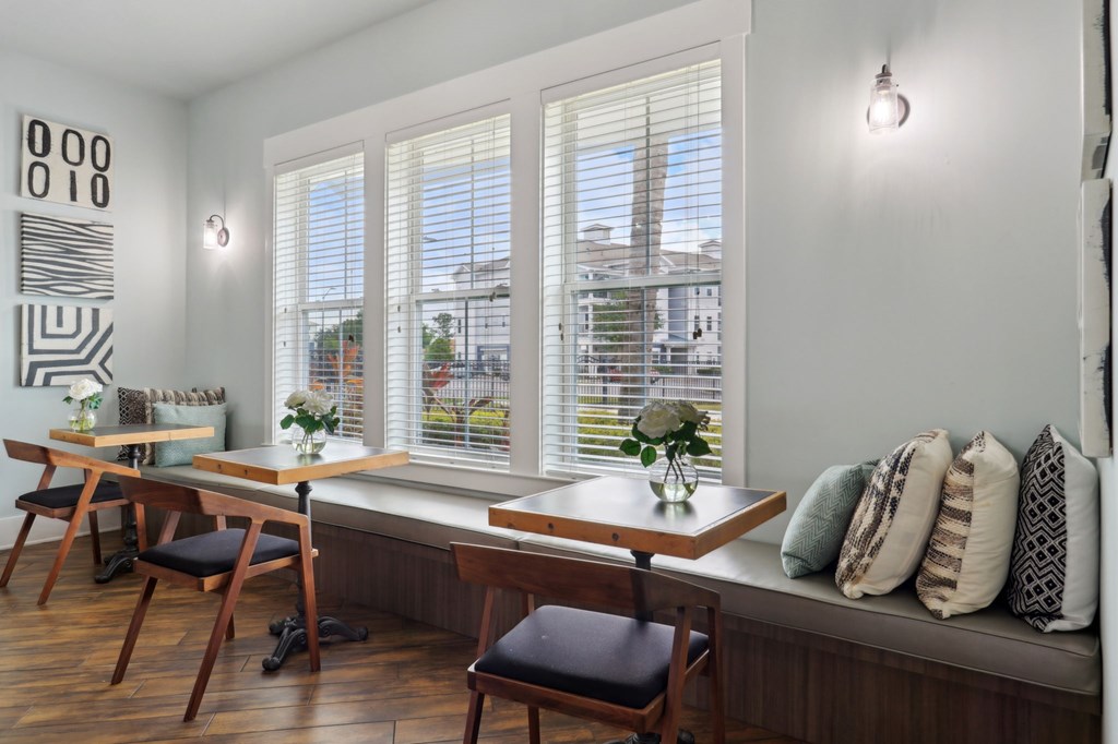 A room with a table and chairs by a window.