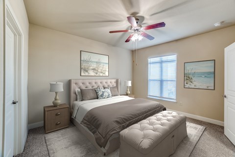 A bedroom with a large bed, a ceiling fan, and two pictures on the wall.