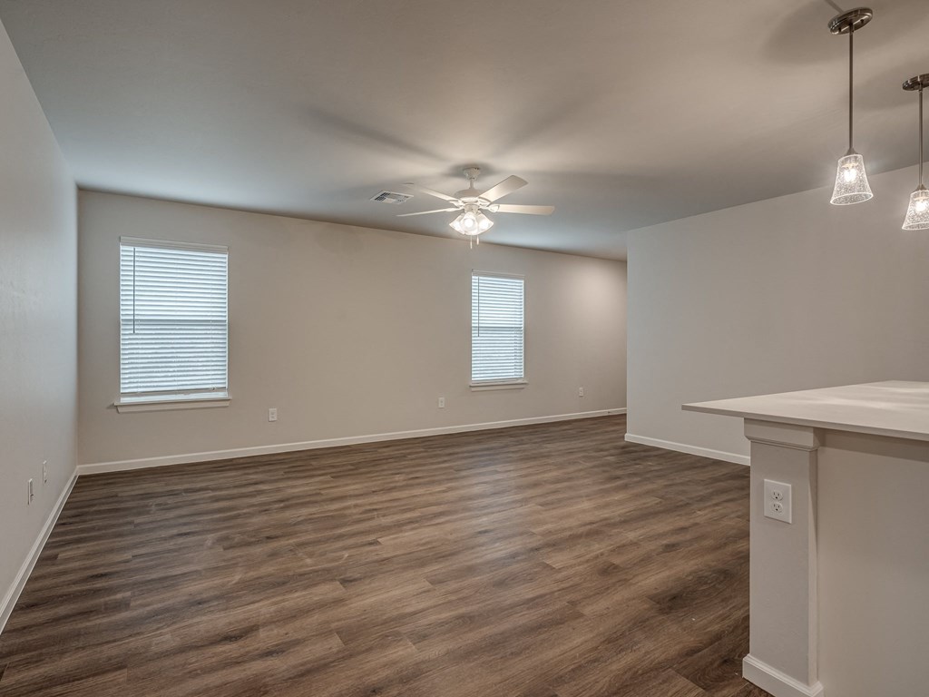 an empty living room with a ceiling fan