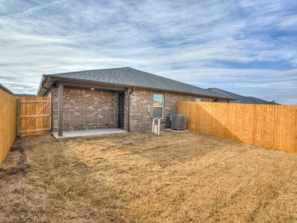 a backyard with a brick house and a wooden fence