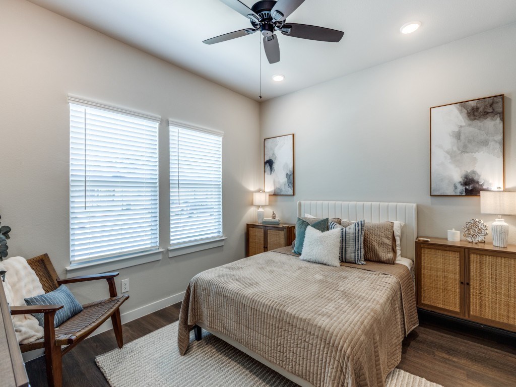 A bedroom with a bed, a chair, and a ceiling fan.