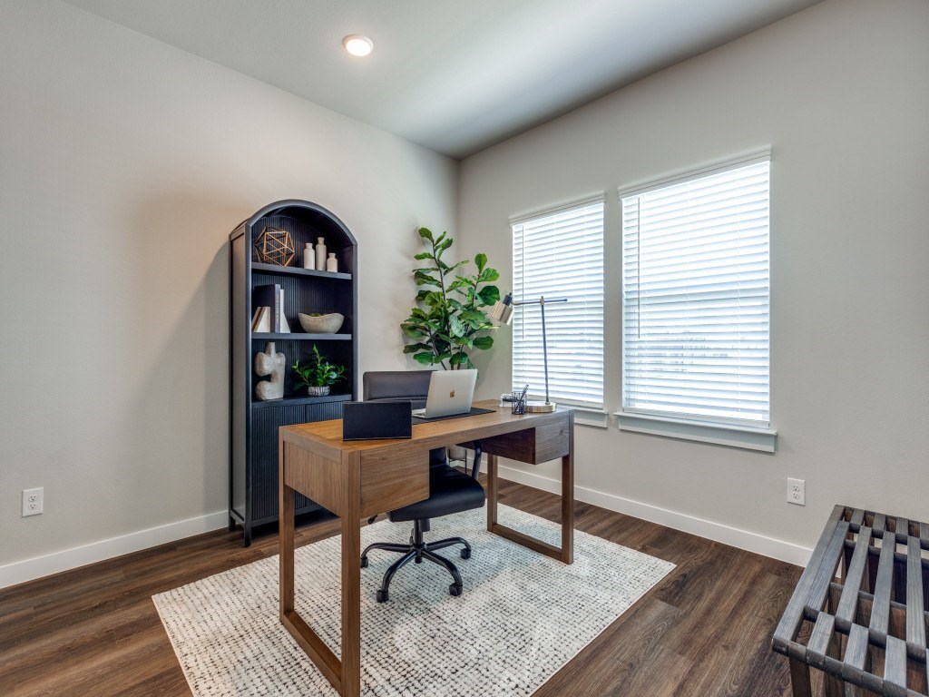 A room with a wooden desk and a laptop on it.