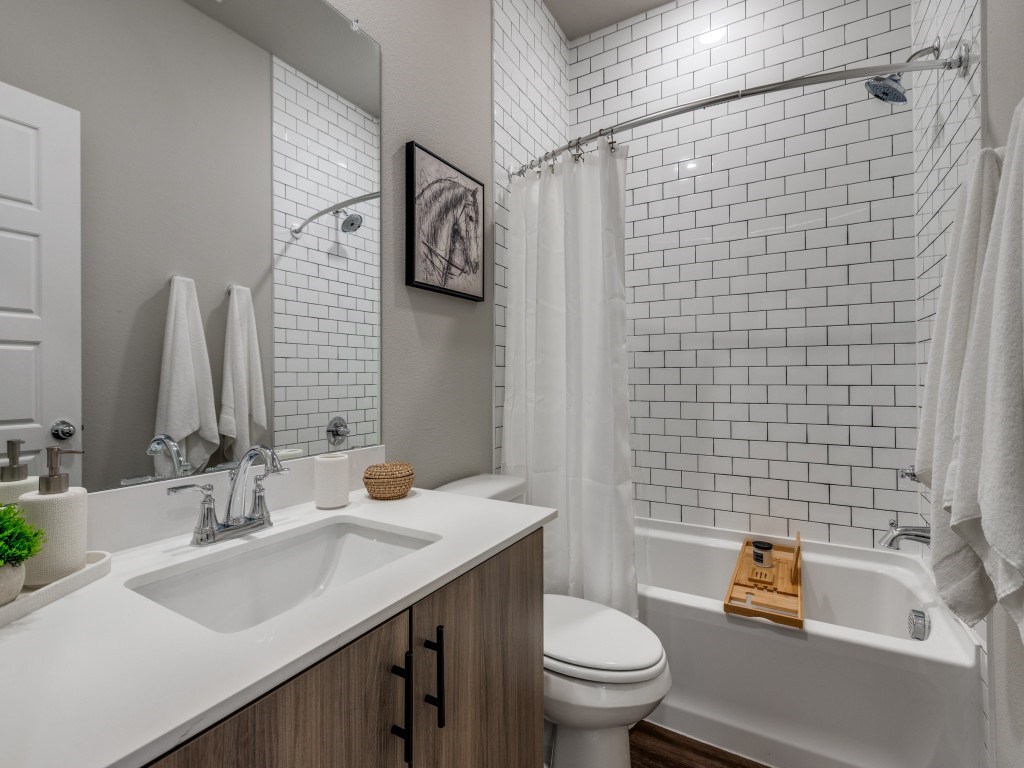 A white bathroom with a white toilet, a white sink, a white tub, and a white shower curtain.