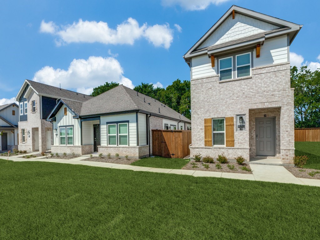 A modern house with a grey roof and a white brick house with a brown door.
