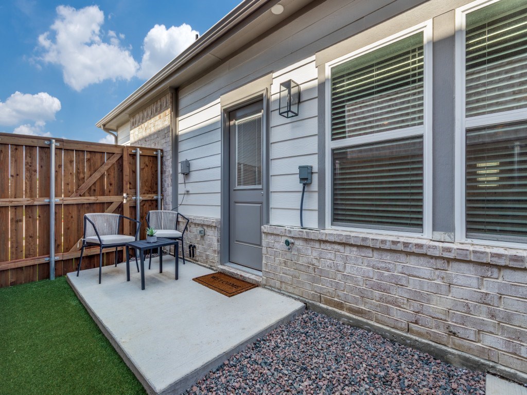 A small patio with a table and chairs is in front of a house.