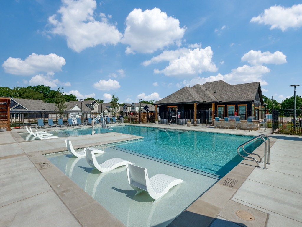A large swimming pool with white chairs and a building in the background.