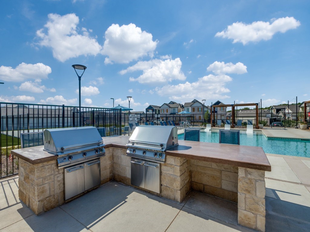 A BBQ grill is on a patio next to a pool.