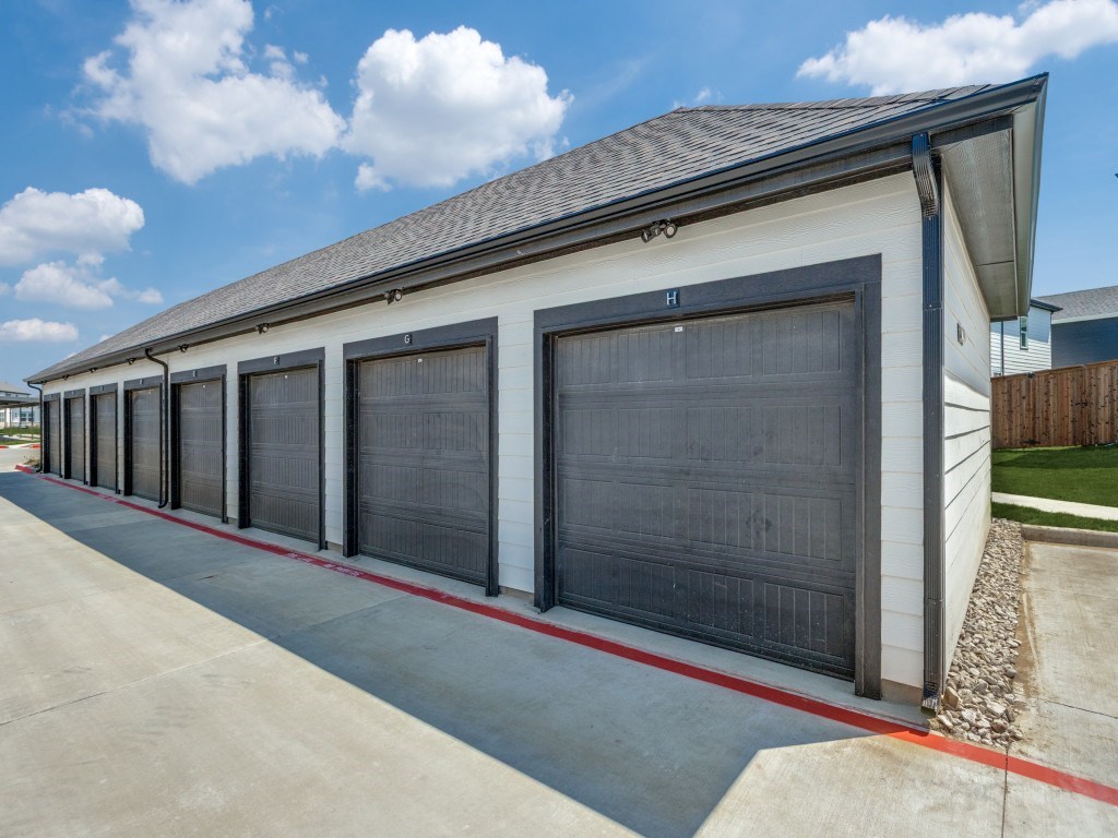 A long white building with a black roof and a garage door.