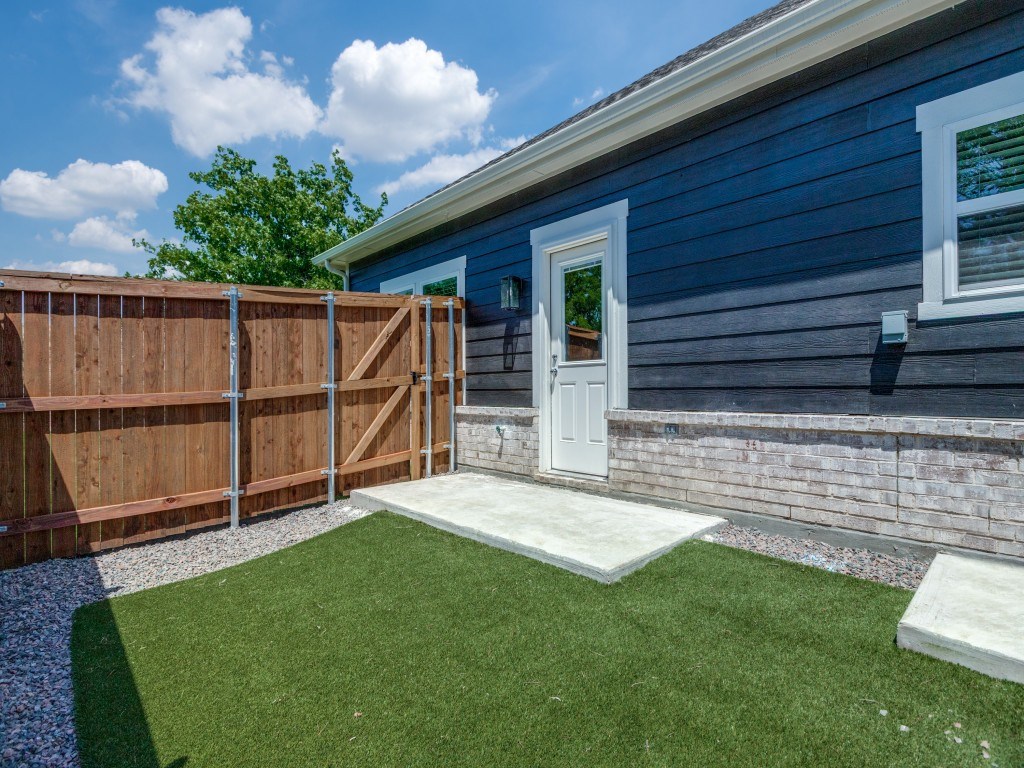 A blue house with a white door and a wooden fence.