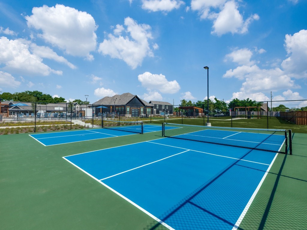 A tennis court with blue and green surface and white lines.