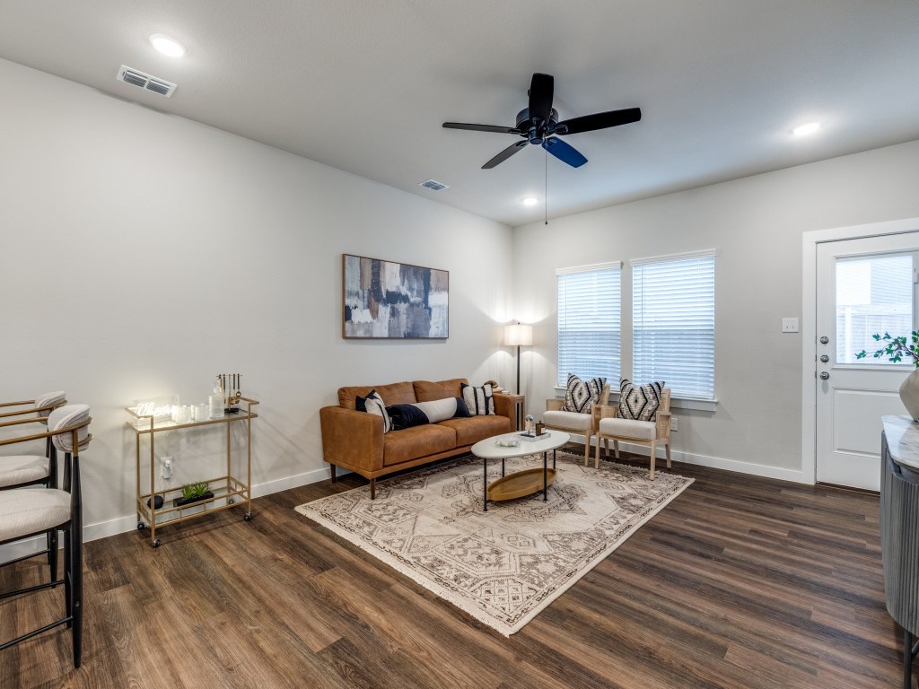 A living room with a brown couch, a rug, and a ceiling fan.