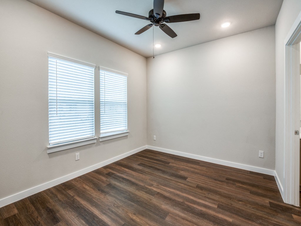 A room with a ceiling fan and wooden flooring.
