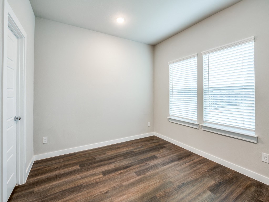 A room with wooden flooring and a window with blinds.