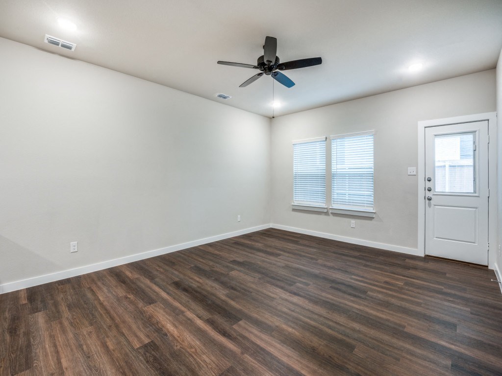 A room with a ceiling fan and wooden flooring.
