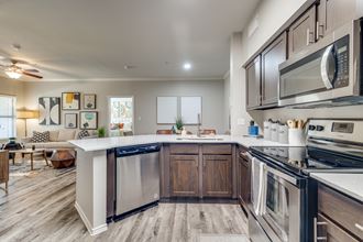 an open kitchen with stainless steel appliances and a white counter top