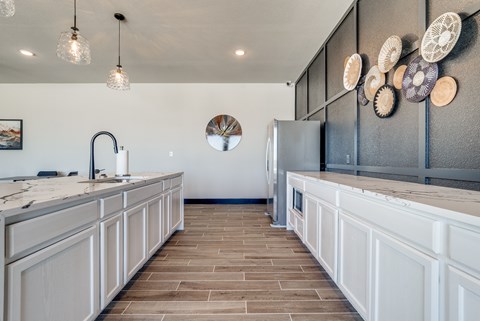 A kitchen with a white counter top and a grey refrigerator.