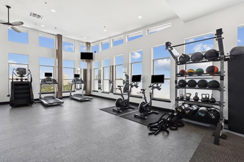 A spacious gym with a variety of exercise equipment and a large window.