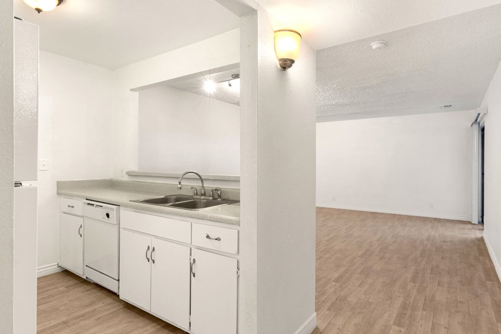 an empty kitchen with white cabinets and a sink