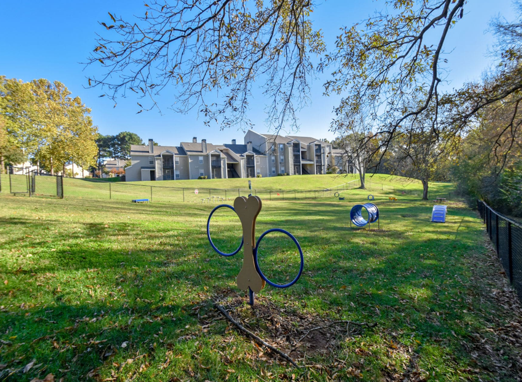 a park with a large building in the background and a pair of scissors in the foreground