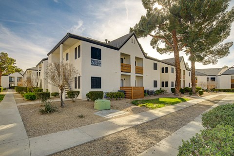 a street view of a white apartment complex with a tree in the foreground