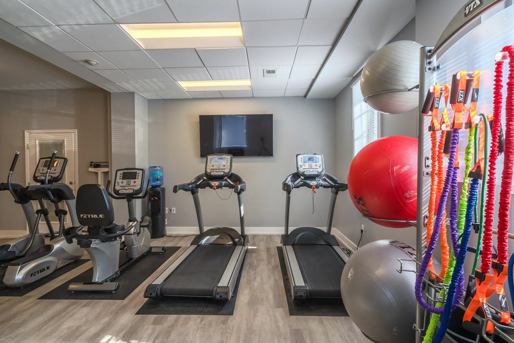 a gym with exercise machines and a tv on the wall