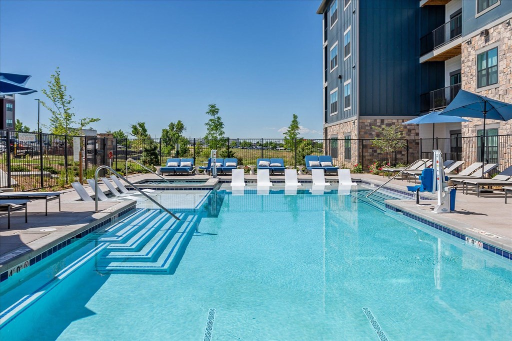 a swimming pool with lounge chairs and a building in the background