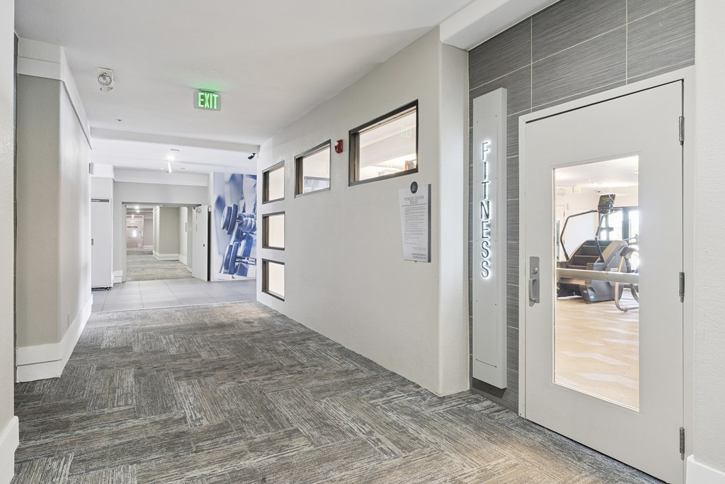A hallway with a carpeted floor and a white door on the right.
