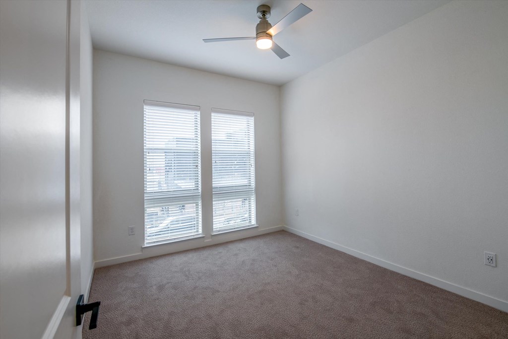 a bedroom with two windows and a ceiling fan