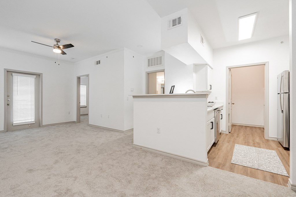 an empty living room and kitchen with white walls and wood flooring