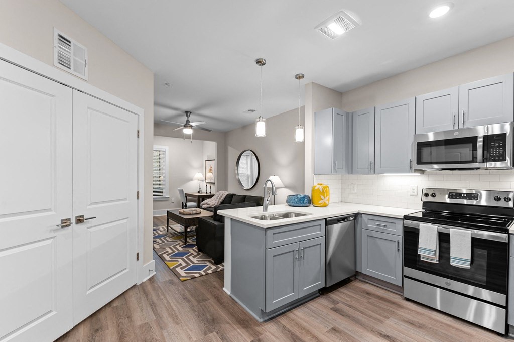a kitchen and living room with white cabinets and stainless steel appliances