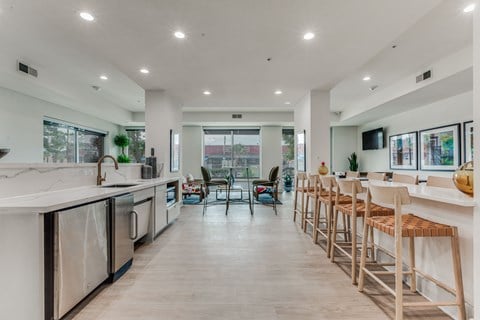 an open kitchen with bar stools and a living room with a table and chairs