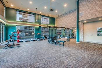 A gym with a variety of equipment including treadmills, weights, and exercise machines.